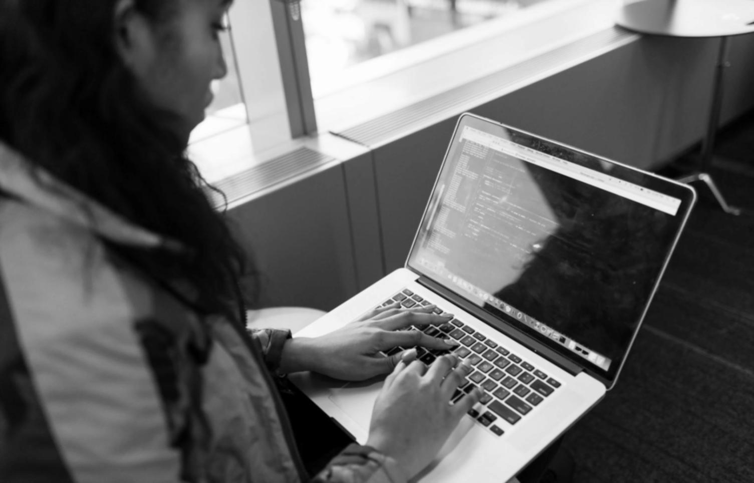 Developers collaborating at a tech conference with multiple screens showing code