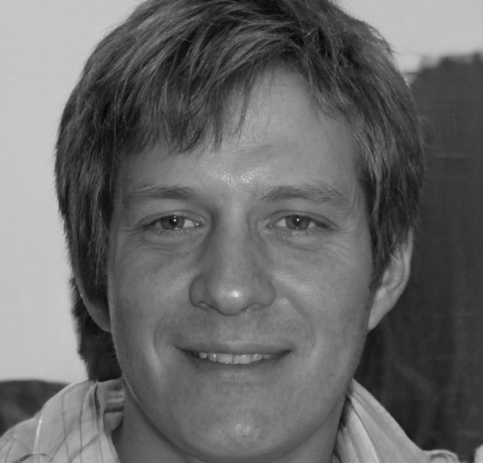 Male speaker with glasses smiling at camera